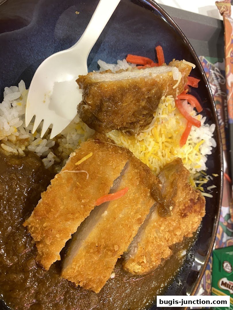 A close-up of a Yoshinoya curry dish with crispy fried pork cutlet and rice.