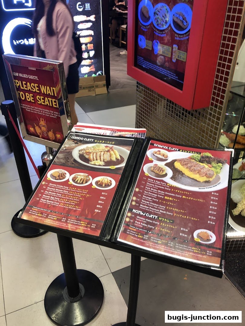A menu stand displaying various curry dishes with prices and images.