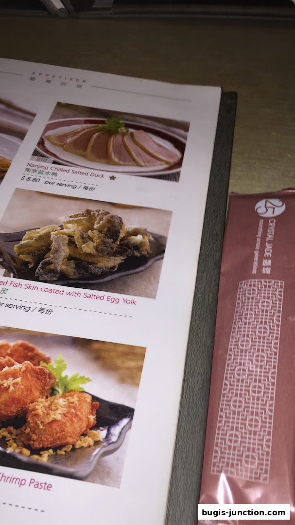 A menu from Crystal Jade La Mian Xiao Long Bao featuring appetizers like salted duck and fried fish skin.