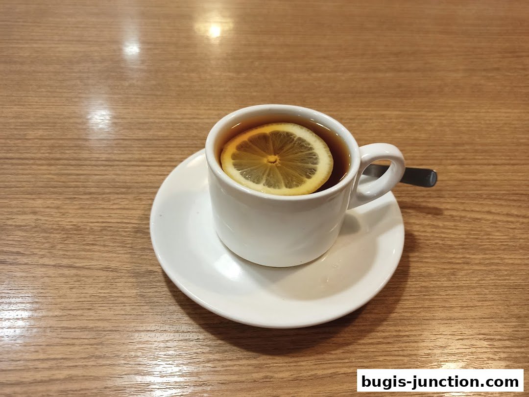 A close-up shot of a white cup of tea with a lemon slice on a saucer.