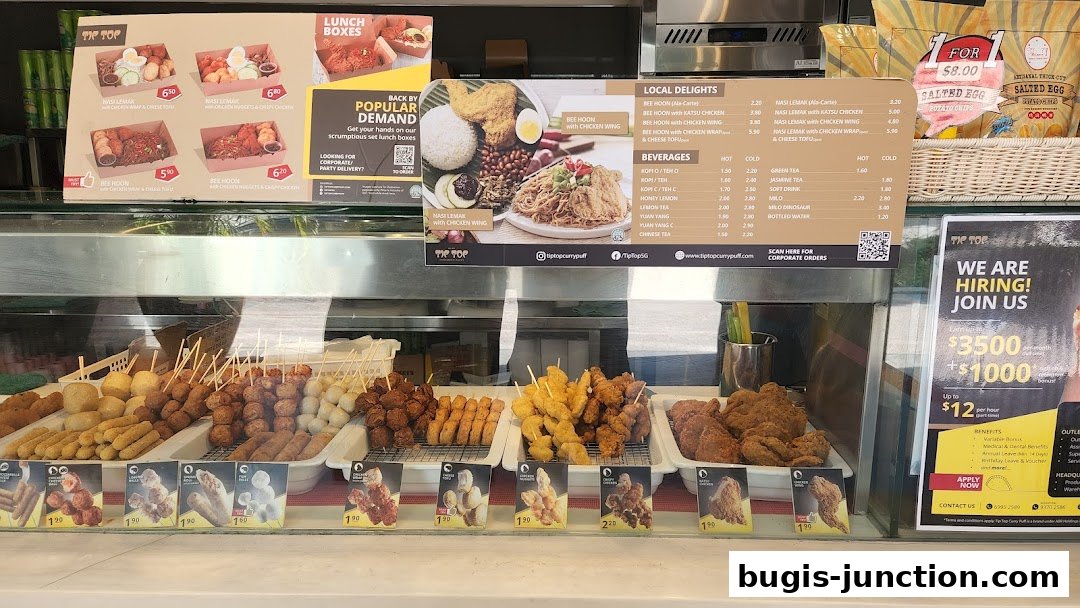 A display of various fried snacks and beverages at a food stall, with a hiring advertisement.