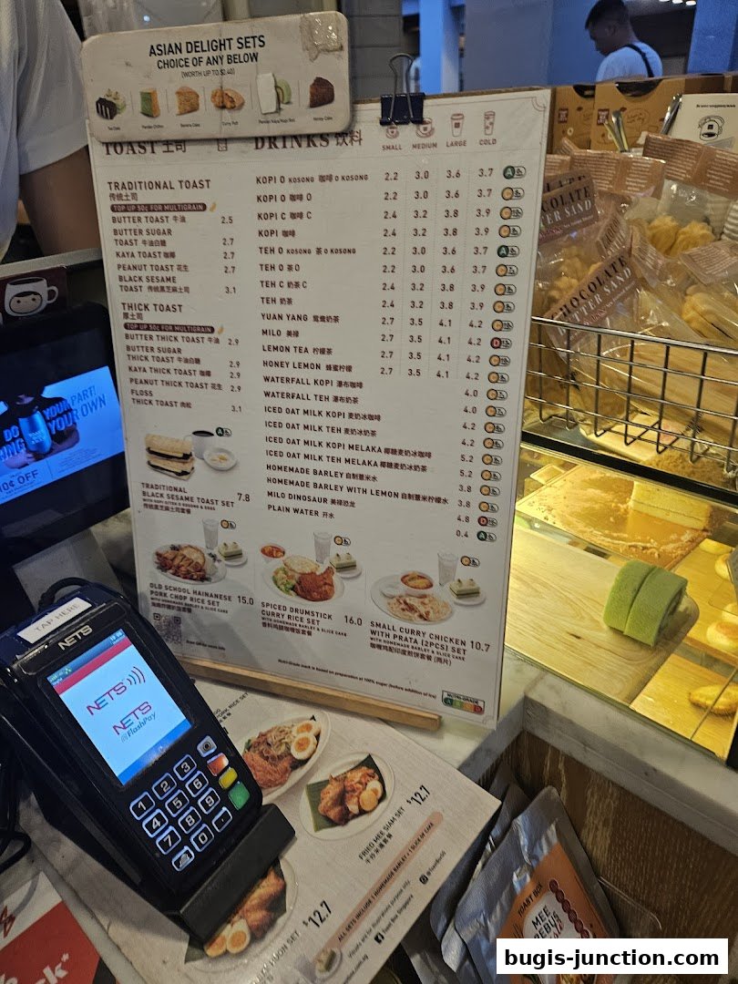 A menu board displaying various toast and drink options with prices, alongside a payment terminal.