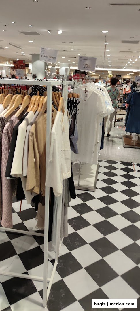 Clothing racks with various garments displayed on hangers inside a store.