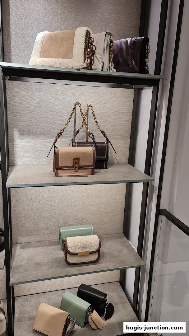 A display of various stylish handbags on shelves in a retail store.