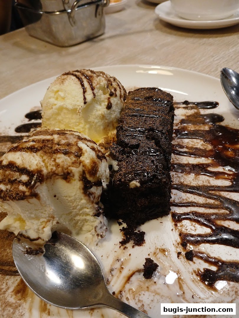 A decadent chocolate brownie served with two scoops of vanilla ice cream and drizzled with chocolate sauce.