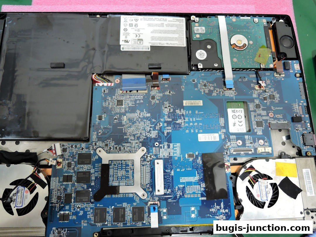 An open laptop showing its internal components, including the motherboard, battery, hard drive, and fans.