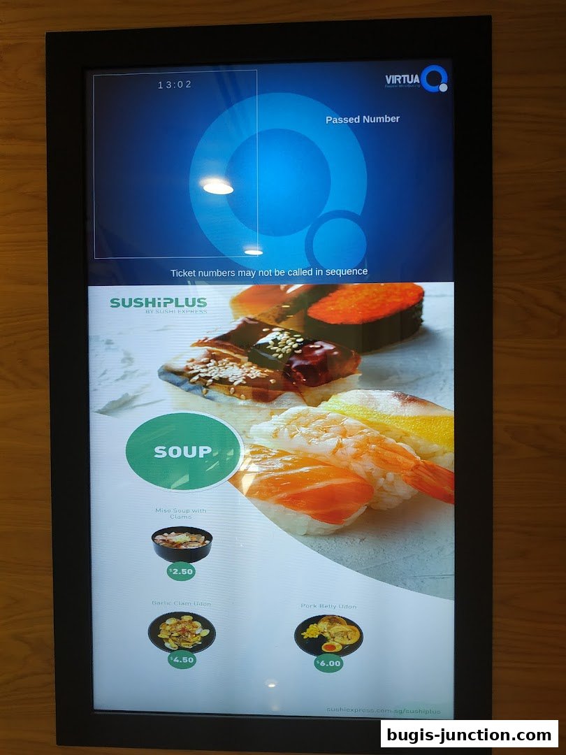 A digital menu board displaying sushi and udon dishes with prices.