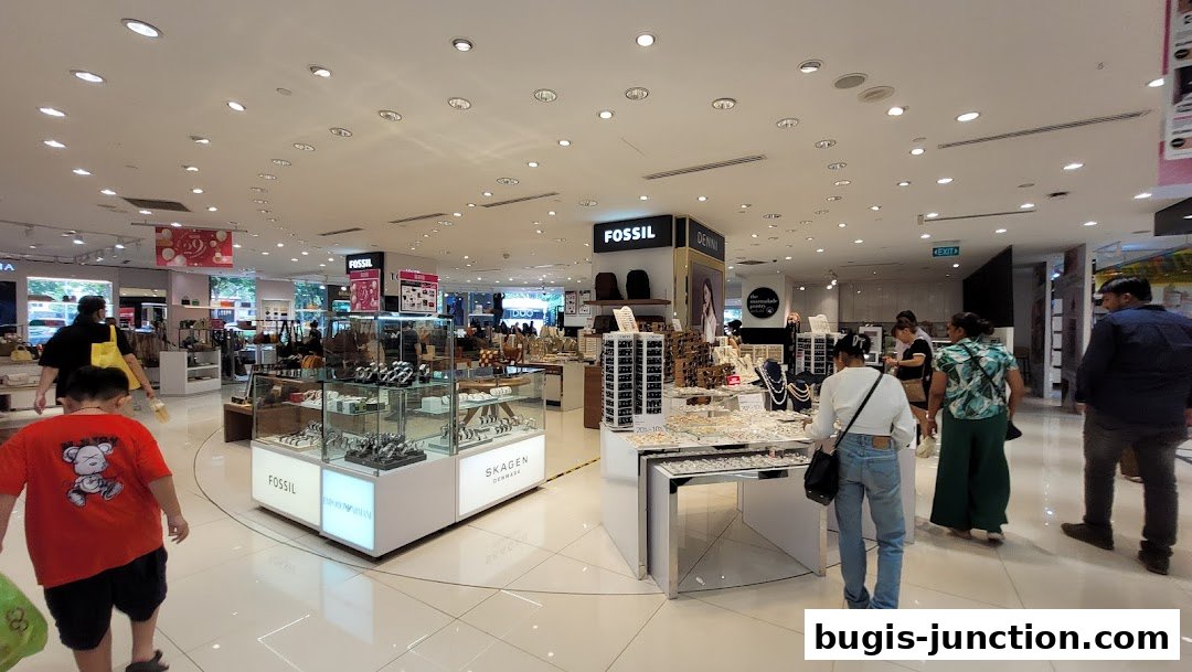 Interior view of a department store section featuring watches, jewelry, and accessories with shoppers browsing.