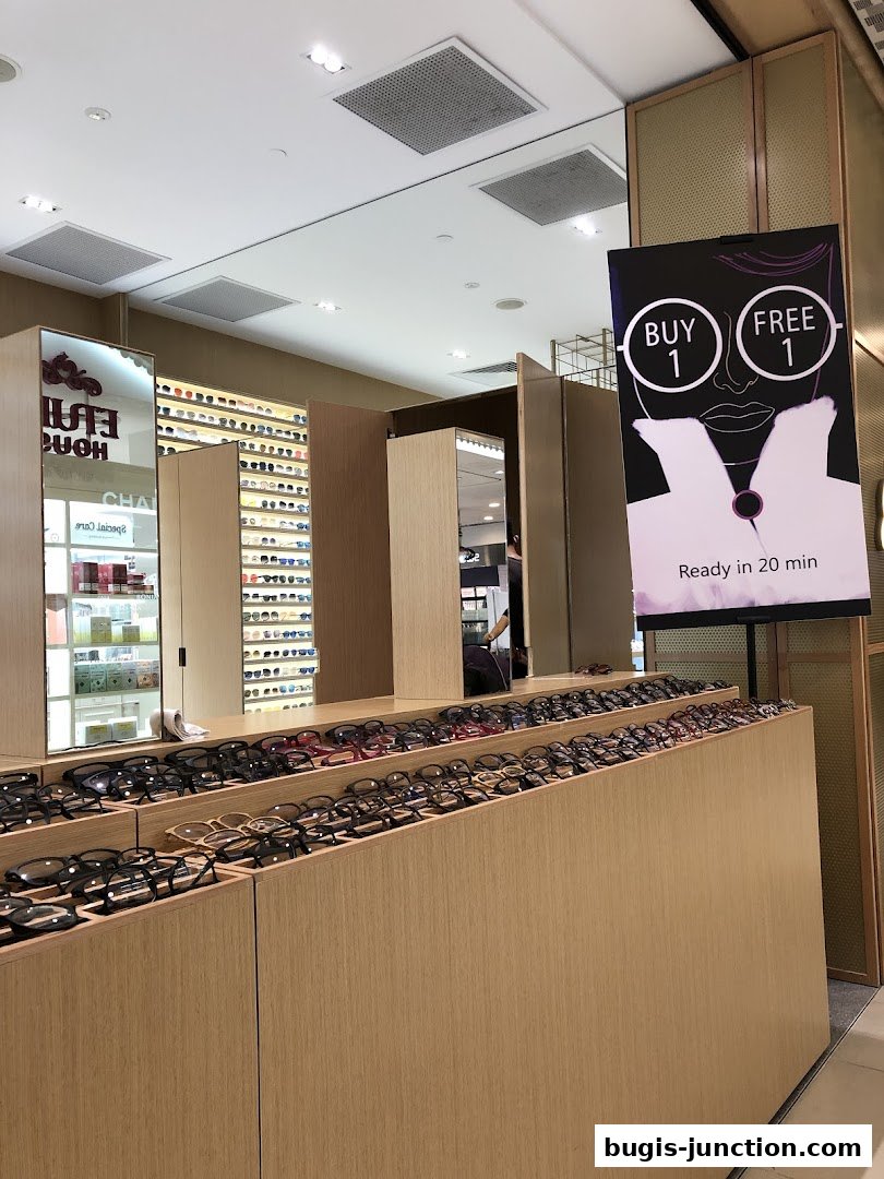 A retail shop interior displaying a wide selection of eyeglasses and a promotional sign.