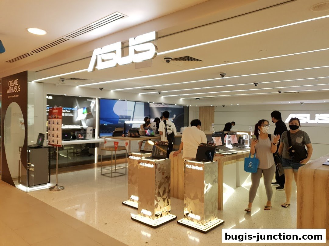 Interior of an ASUS store showcasing laptops and customers browsing.
