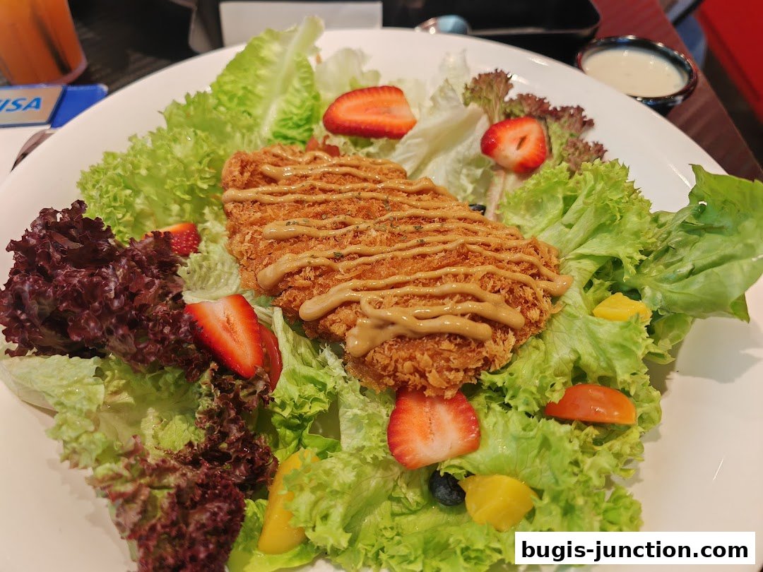 A delicious salad with crispy chicken, fresh lettuce, strawberries, and mango chunks.