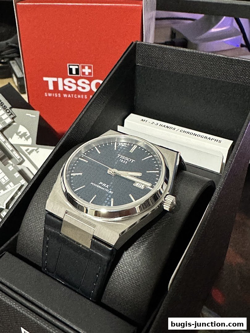 A Tissot PRX Powermatic 80 watch in its box with Tissot branding visible.