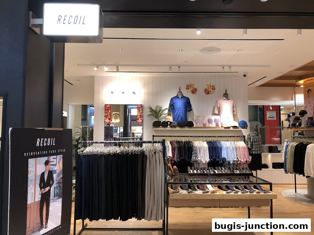 The entrance of RECOIL, a men's fashion store, showcasing shirts, pants, and accessories.
