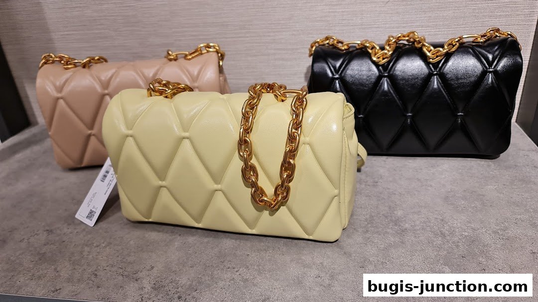 Three quilted handbags with gold chain straps in beige, yellow, and black.