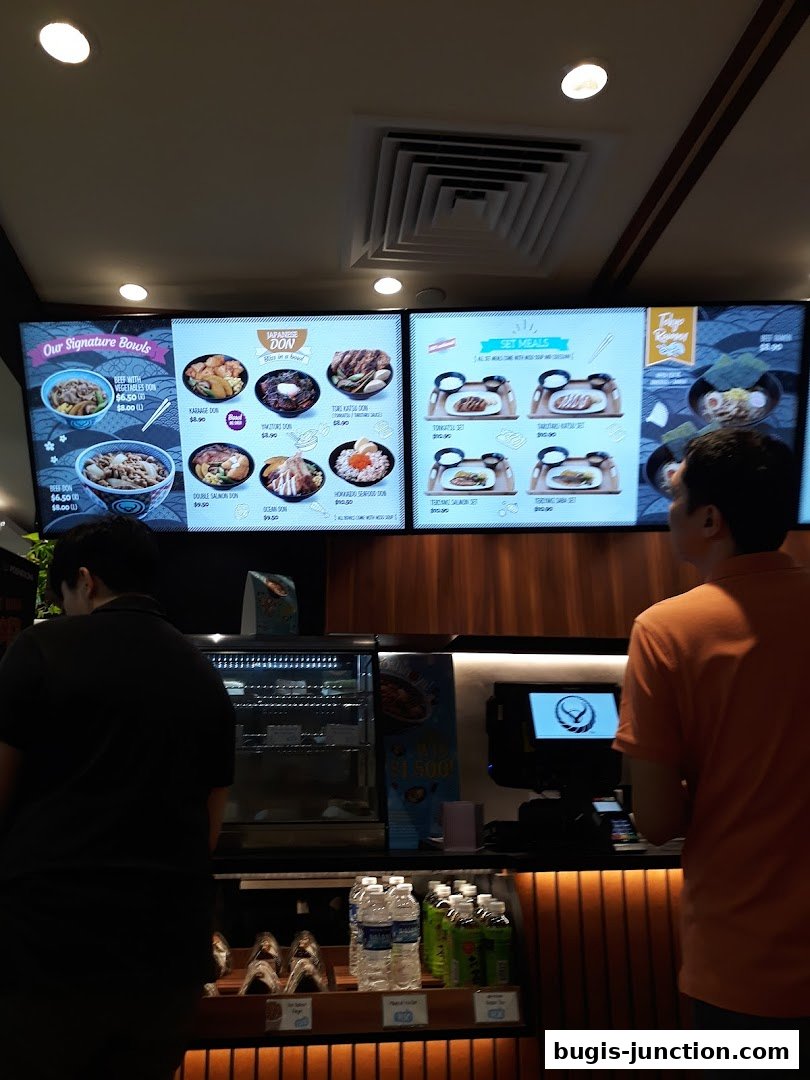 A digital menu board displaying various Japanese donburi bowls and set meals at Yoshinoya.