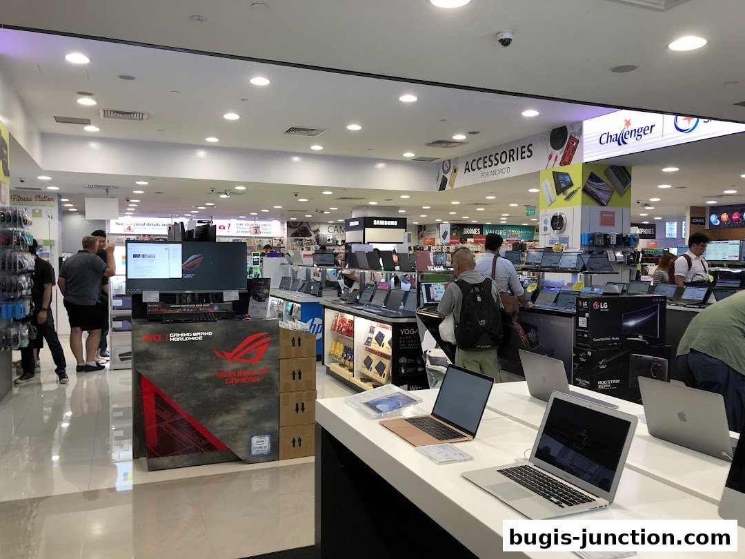 Interior view of a brightly lit electronics store showcasing various laptops and accessories.