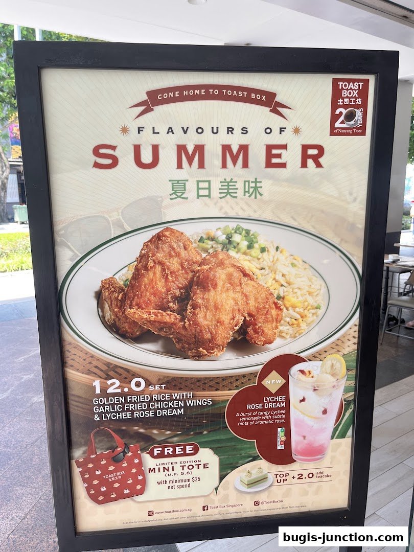 A promotional sign for Toast Box featuring a summer set meal with fried chicken and rice, and a lychee rose drink.