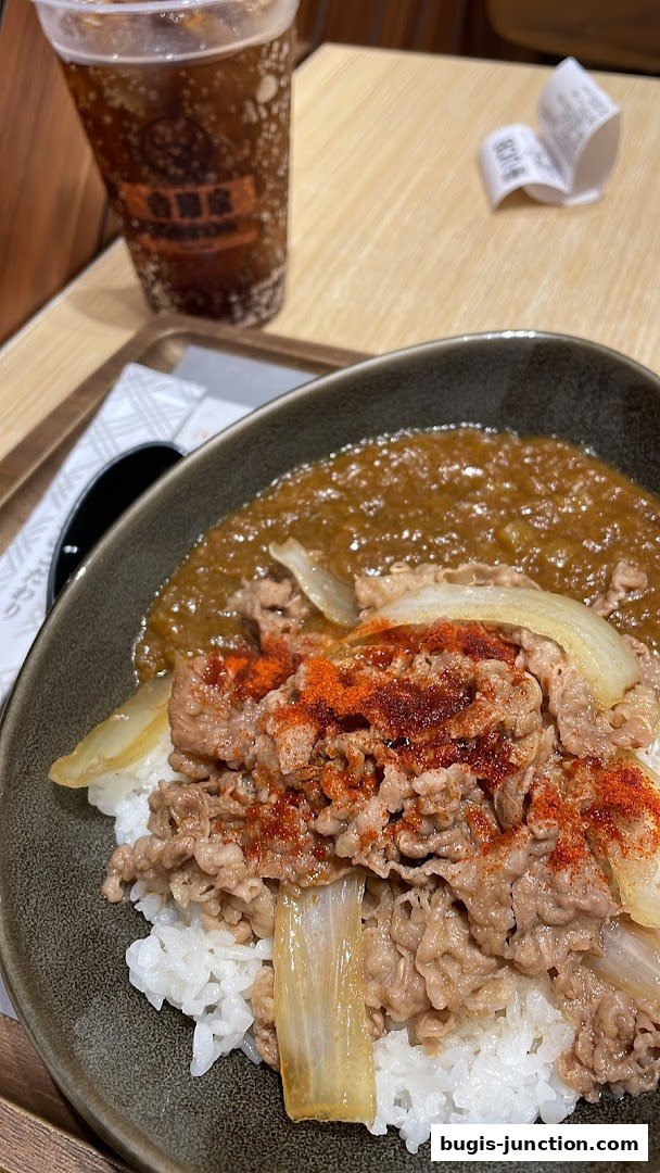 A close-up of a Yoshinoya beef bowl with a side of iced beverage.