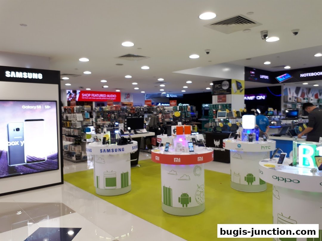 Interior view of a modern electronics store with various brands and products on display.