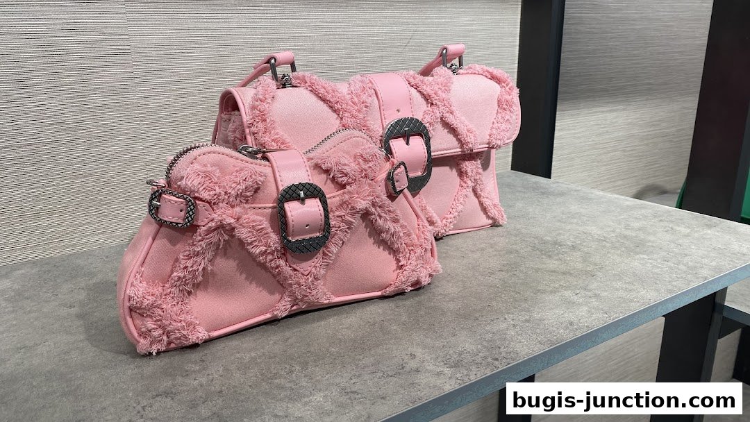 Two pink Charles & Keith handbags with fringe detailing and silver buckles displayed on a counter.