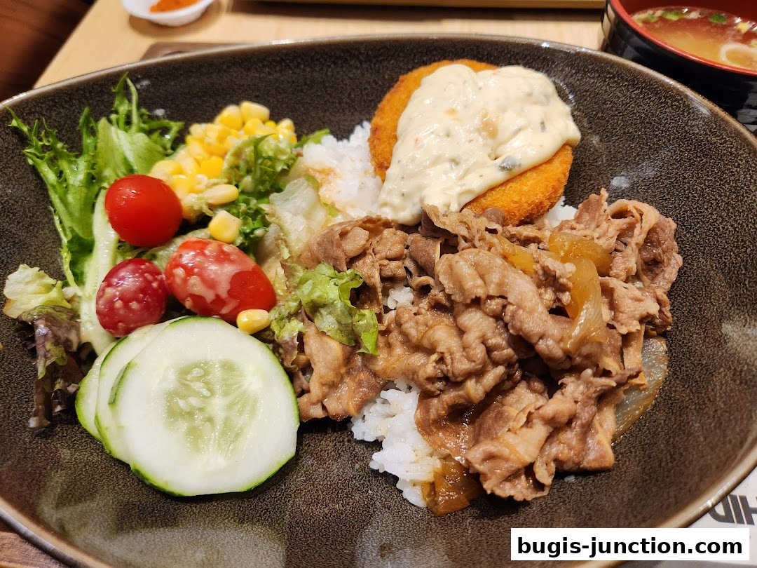 A delicious Yoshinoya beef bowl with salad, fried item, and miso soup.