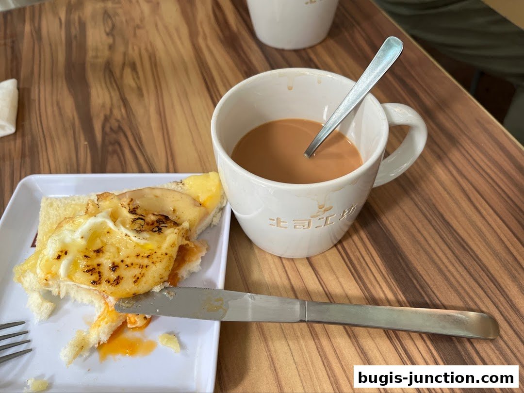 A close-up of a half-eaten toast with egg and cheese, next to a cup of tea.