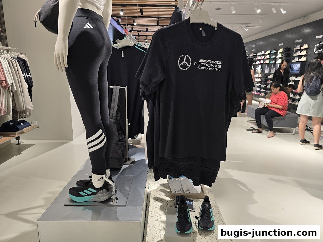 Mannequin wearing Adidas leggings and shoes, with t-shirts and shoes displayed in a store.