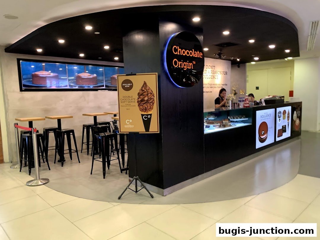 Chocolate Origin shop with a display of cakes, seating area, and a counter with staff.
