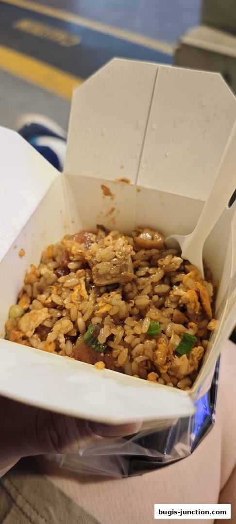 A close-up of a takeaway box filled with delicious fried rice and a fork.