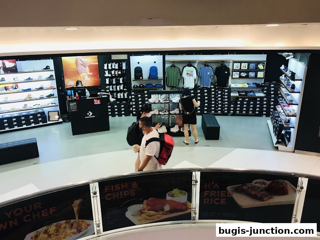 Interior view of a Converse store showcasing shoes, apparel, and accessories with customers browsing.