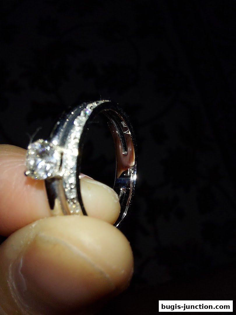 A hand holds a sparkling diamond ring with intricate detailing and a 750 hallmark.