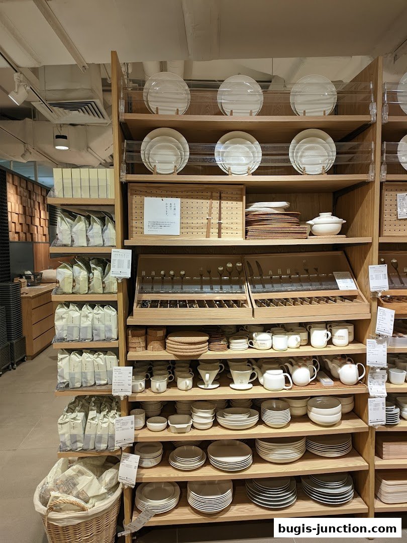 Shelves filled with various tableware, including plates, bowls, cups, and cutlery, at MUJI.