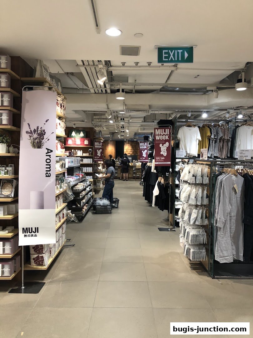 Interior view of a MUJI store showcasing clothing and home goods with promotional signage.