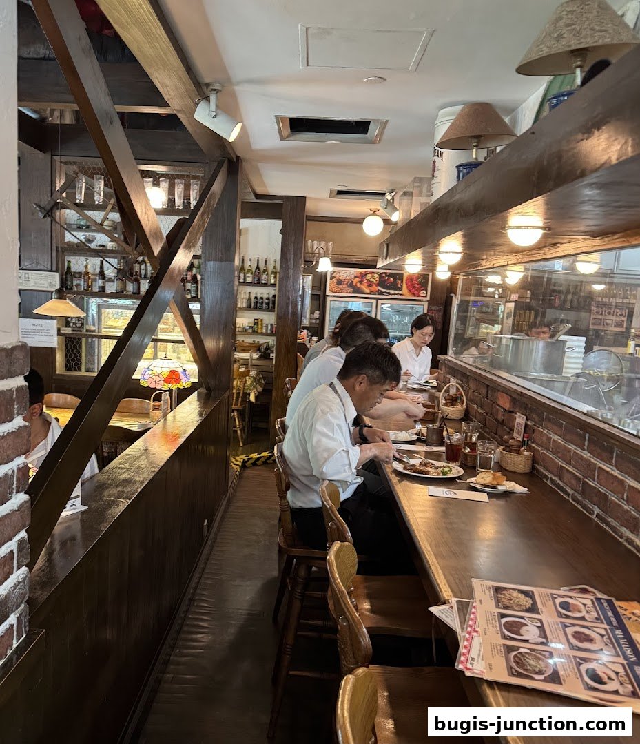 Diners seated at a wooden counter in a cozy restaurant with exposed brick and warm lighting.