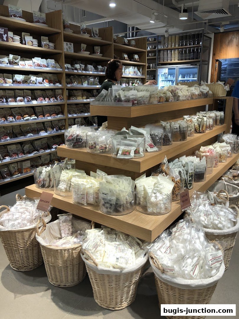 Interior view of a MUJI store showcasing shelves filled with packaged food items and baskets of snacks.