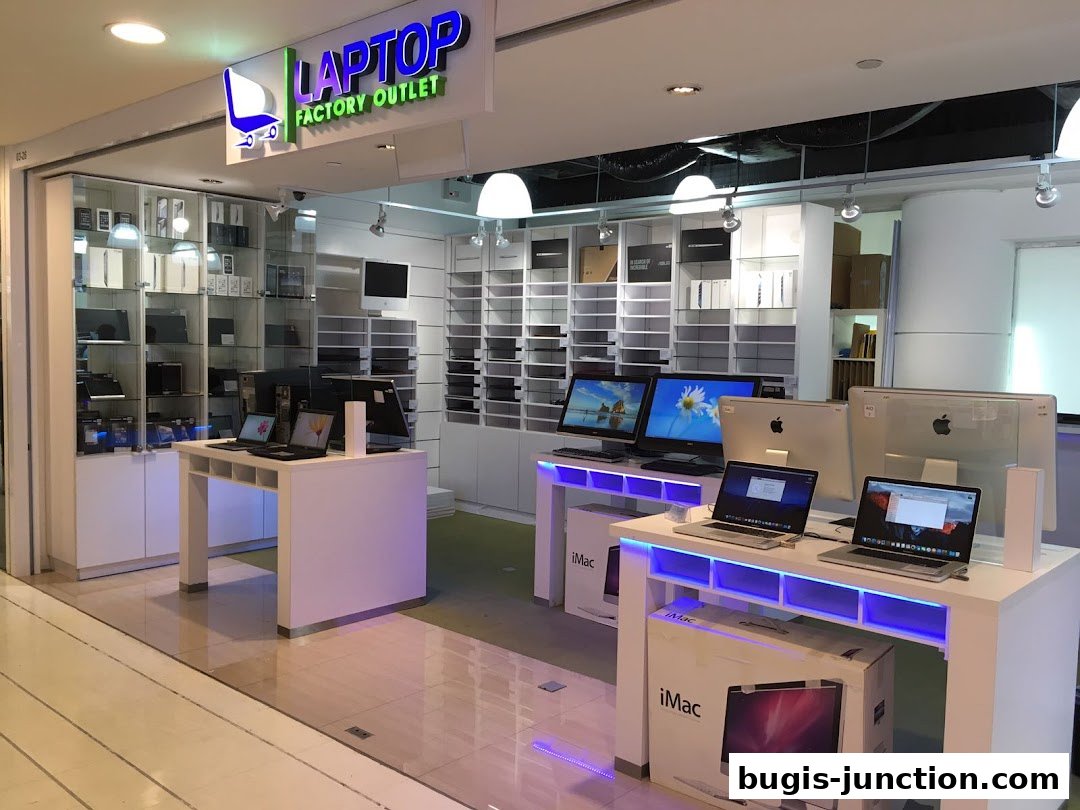 Interior view of a modern electronics store showcasing laptops and iMacs on display.