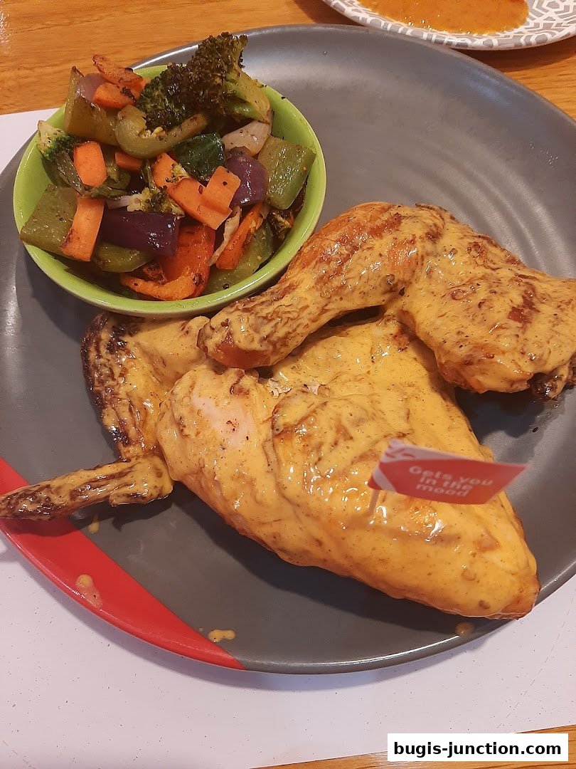 Flame-grilled chicken with a side of roasted vegetables on a grey plate.