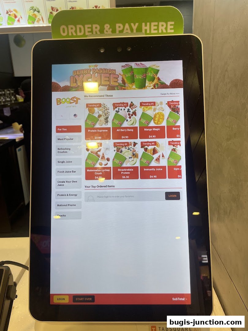 A digital kiosk displays Boost Juice menu items and ordering options.