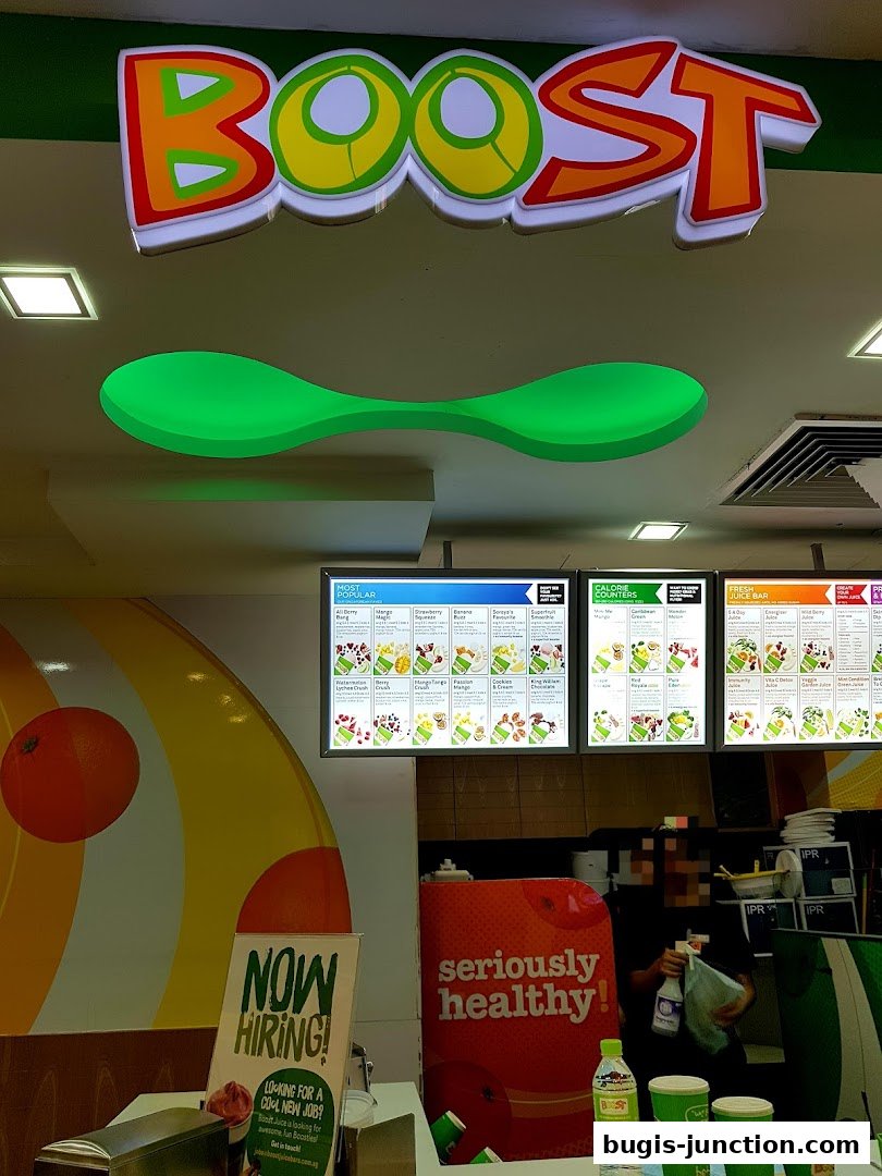 The interior of a Boost Juice shop with a prominent logo, menu boards, and hiring signage.