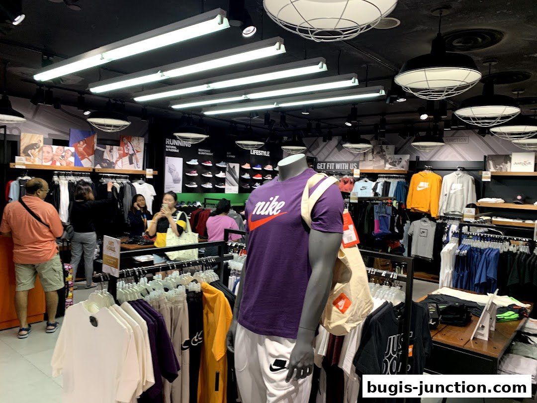 Interior of a Nike store with clothing displays, mannequins, and shoppers.