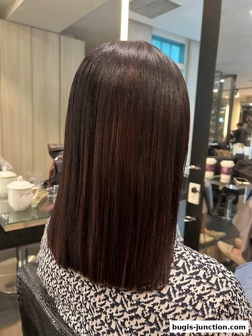 A person with freshly cut, sleek, dark brown hair sitting in a salon chair.
