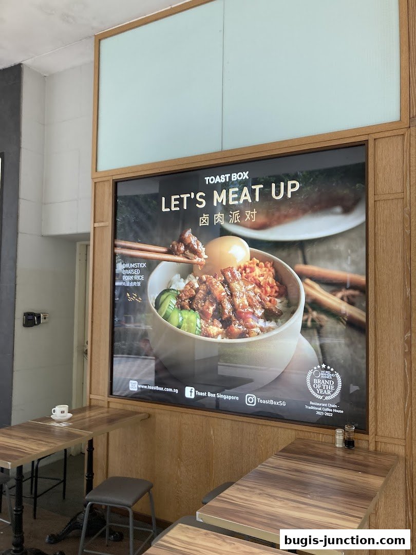 A large advertisement for Toast Box featuring a bowl of braised pork rice.
