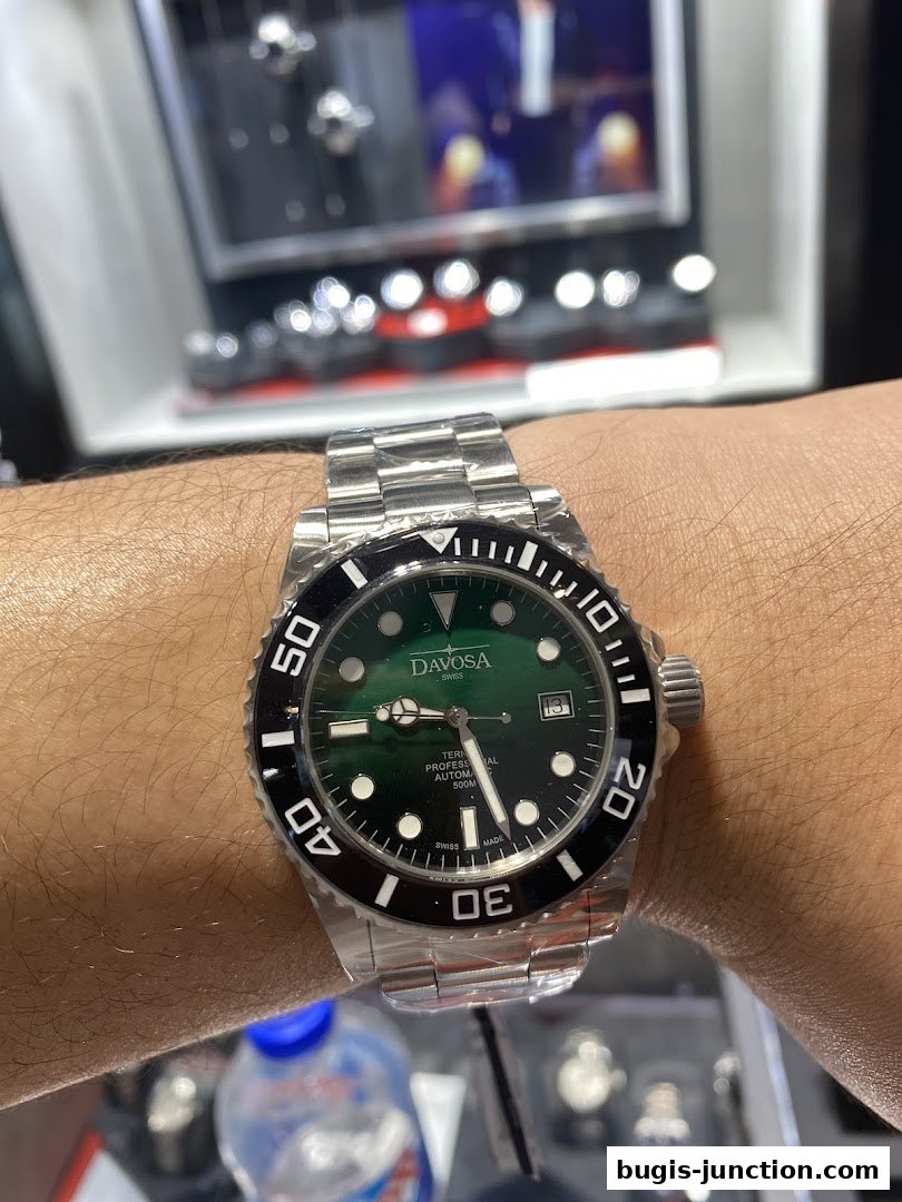A close-up shot of a person wearing a green dial Davosa automatic watch.