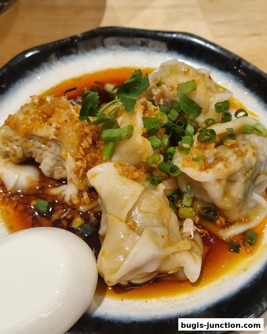 A close-up shot of delicious wontons in chili oil, garnished with scallions and crispy garlic.