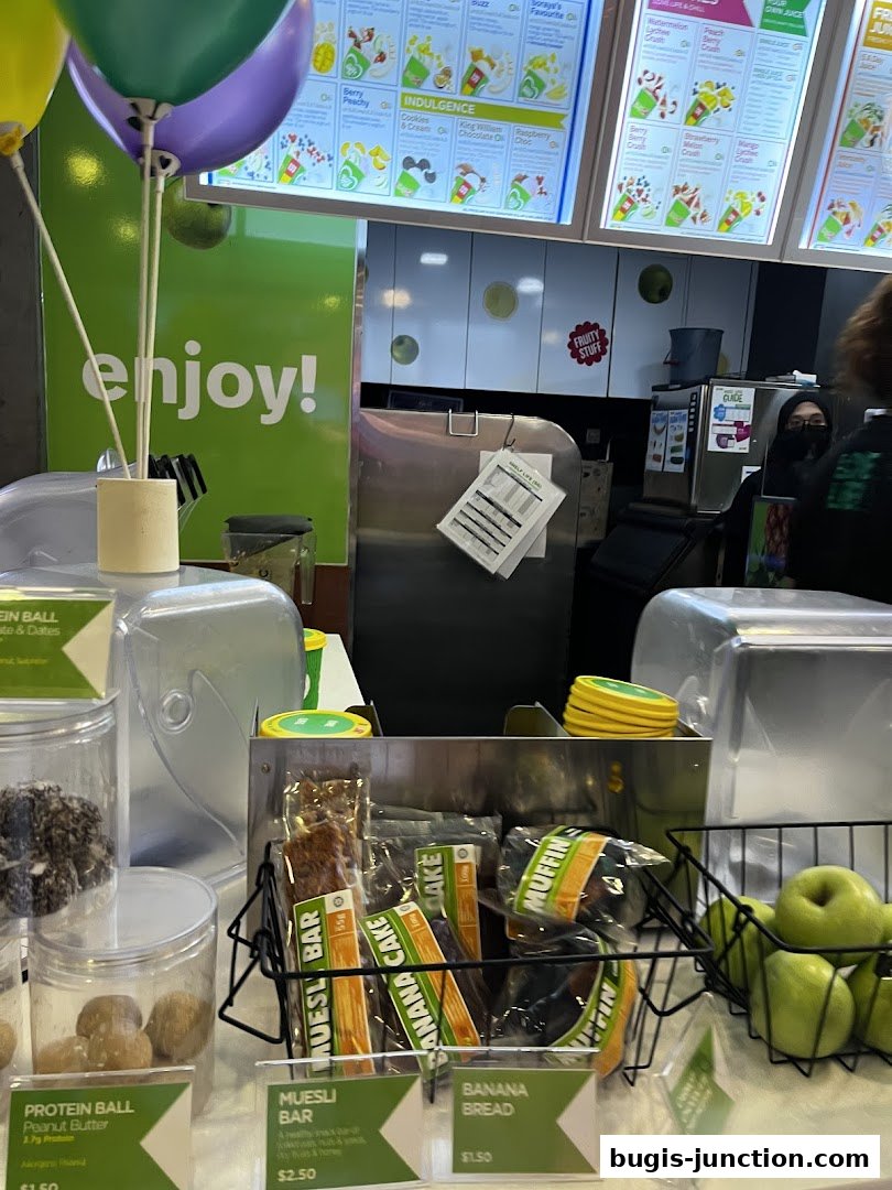 A Boost Juice counter displaying various healthy snacks and a menu board with colorful fruit illustrations.
