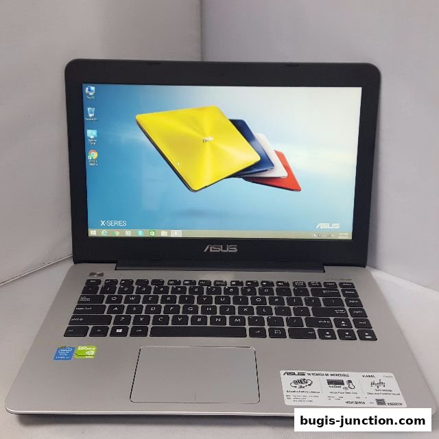 A silver ASUS X-Series laptop with a colorful wallpaper displayed on its screen.