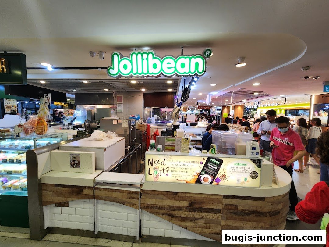 The Jollibean shop counter with customers and a display of pastries.