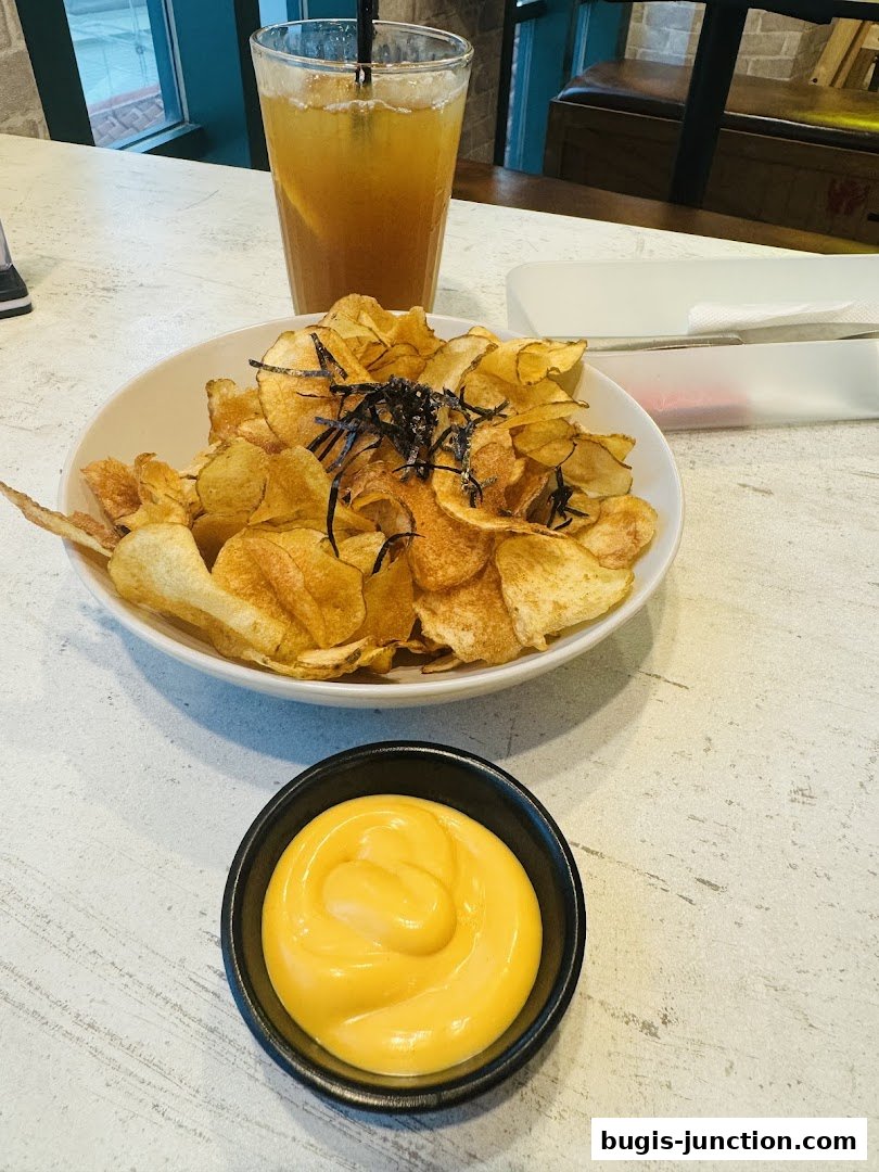 A bowl of crispy potato chips with seaweed and a glass of iced tea.