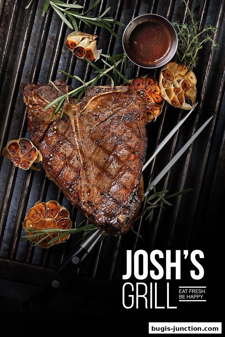 A perfectly grilled T-bone steak with roasted garlic and rosemary on a grill.