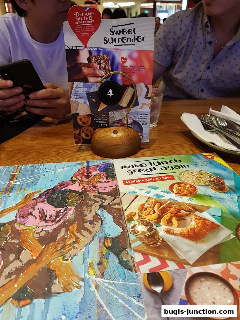 A table setting with menus and people dining at Nandos Bugis Junction.